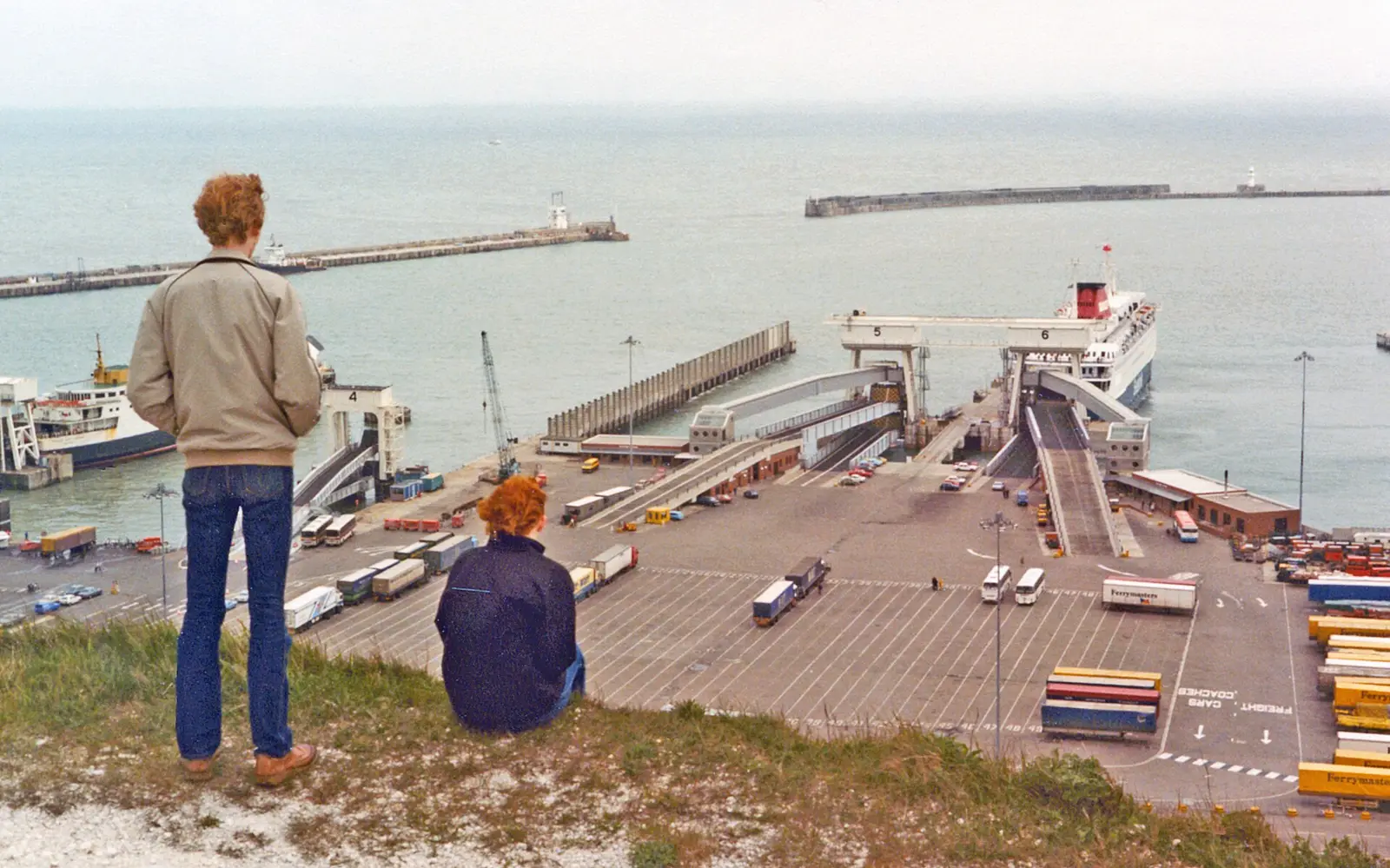 Two people sitting on the cliff above the Eastern Docks at Dover, looking at the ferry terminal, in 1983